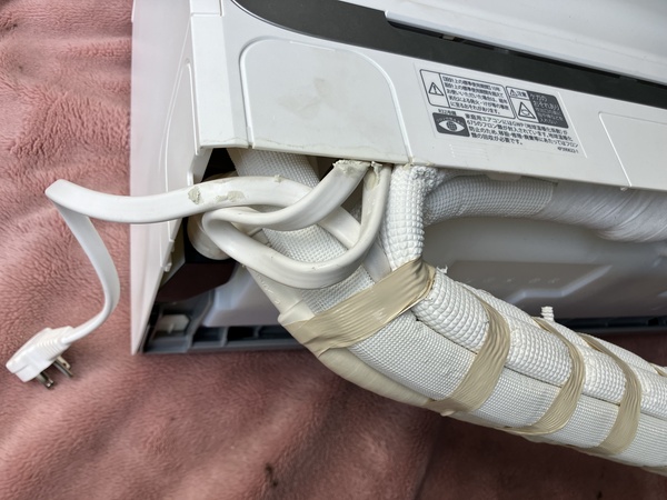 エアコン室内機の背面にまとめられた配管と電源コード